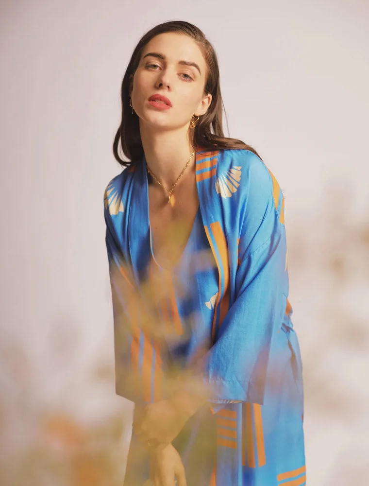 Woman in blue kimono with orange accents posing in front of beige background