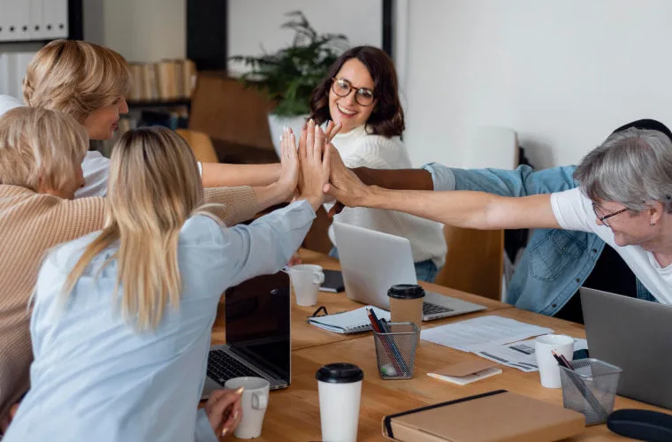 Diverse team celebrating success with high five in modern office