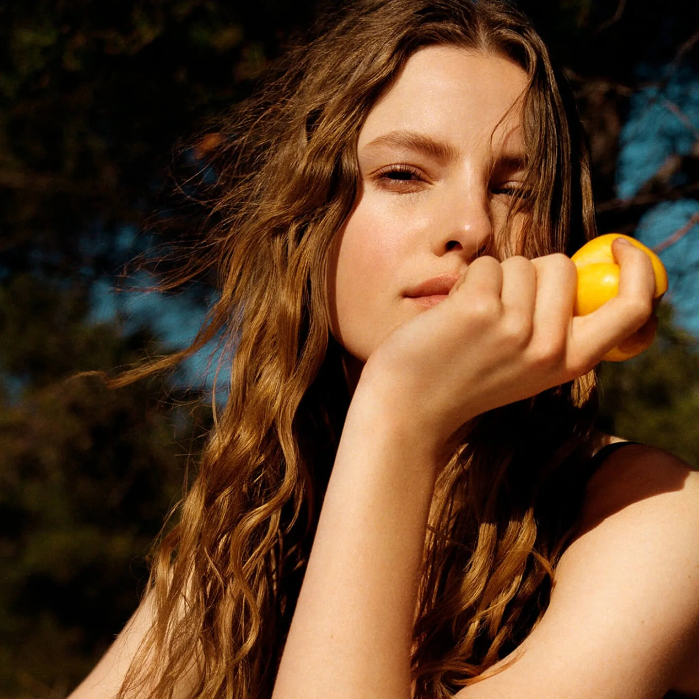 Young woman with long brown hair holding a lemon