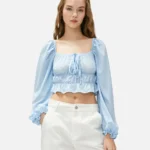 Young woman in light blue blouse and white pants posing on white background