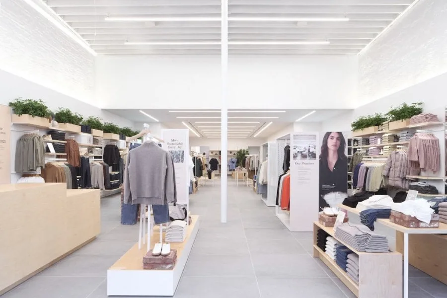 Modern clothing store interior with neatly arranged racks and shelves of clothes, shoes, and accessories.