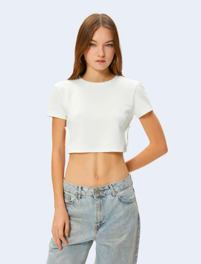 Young woman in white cropped t-shirt and light blue jeans posing